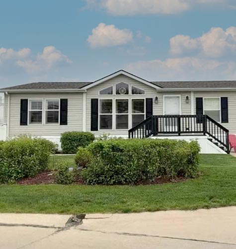 A beautiful Hames Homes with large windows and a nice porch is displayed with a blue sky and green grass