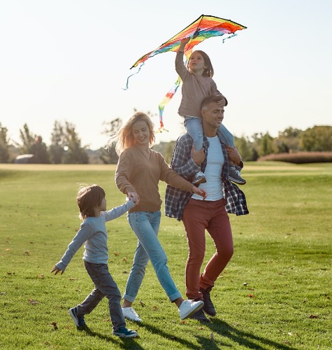 A family flies a kite in a bright green outdoor location
