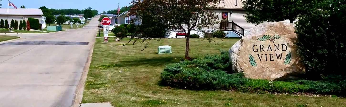 A rock with the name "Grand View" enscribed on it sits in a green yard