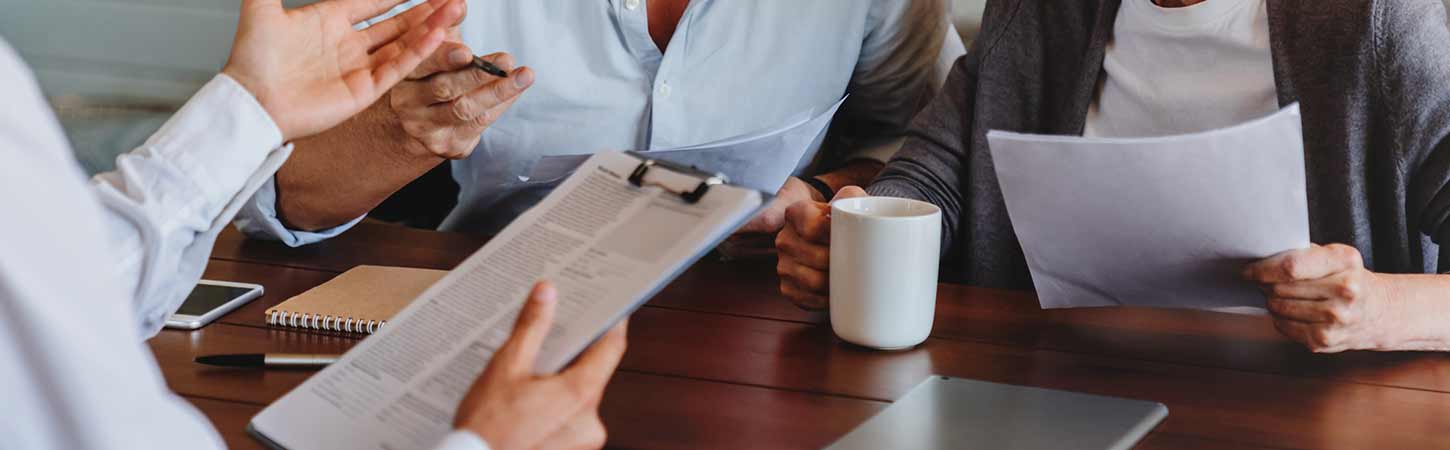 A couple talks with an insurance broker over a table