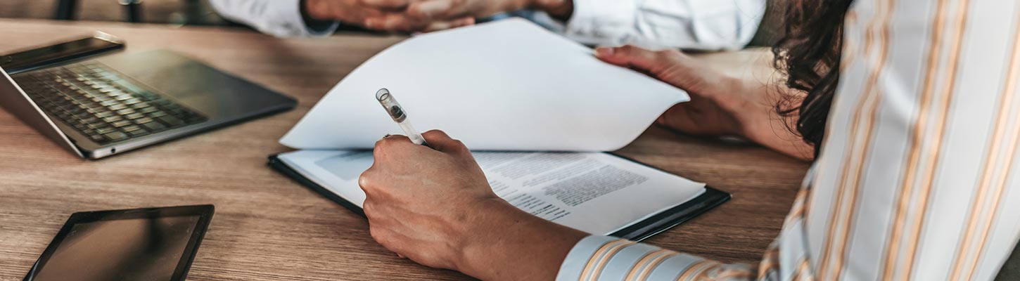 People flip pages and use a pen at a table