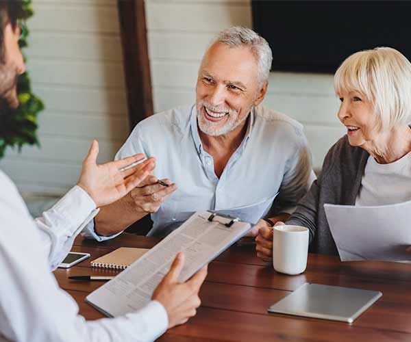 An elderly couple discusses financing with a person at a desk